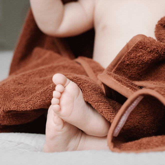 petits pieds de bébé dans cape de bain en éponge