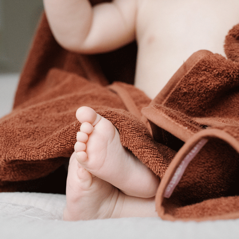 petits pieds de bébé dans cape de bain en éponge