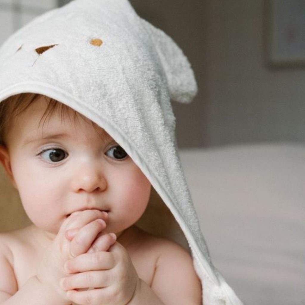 bébé avec capuche de cape de bain sur la tête