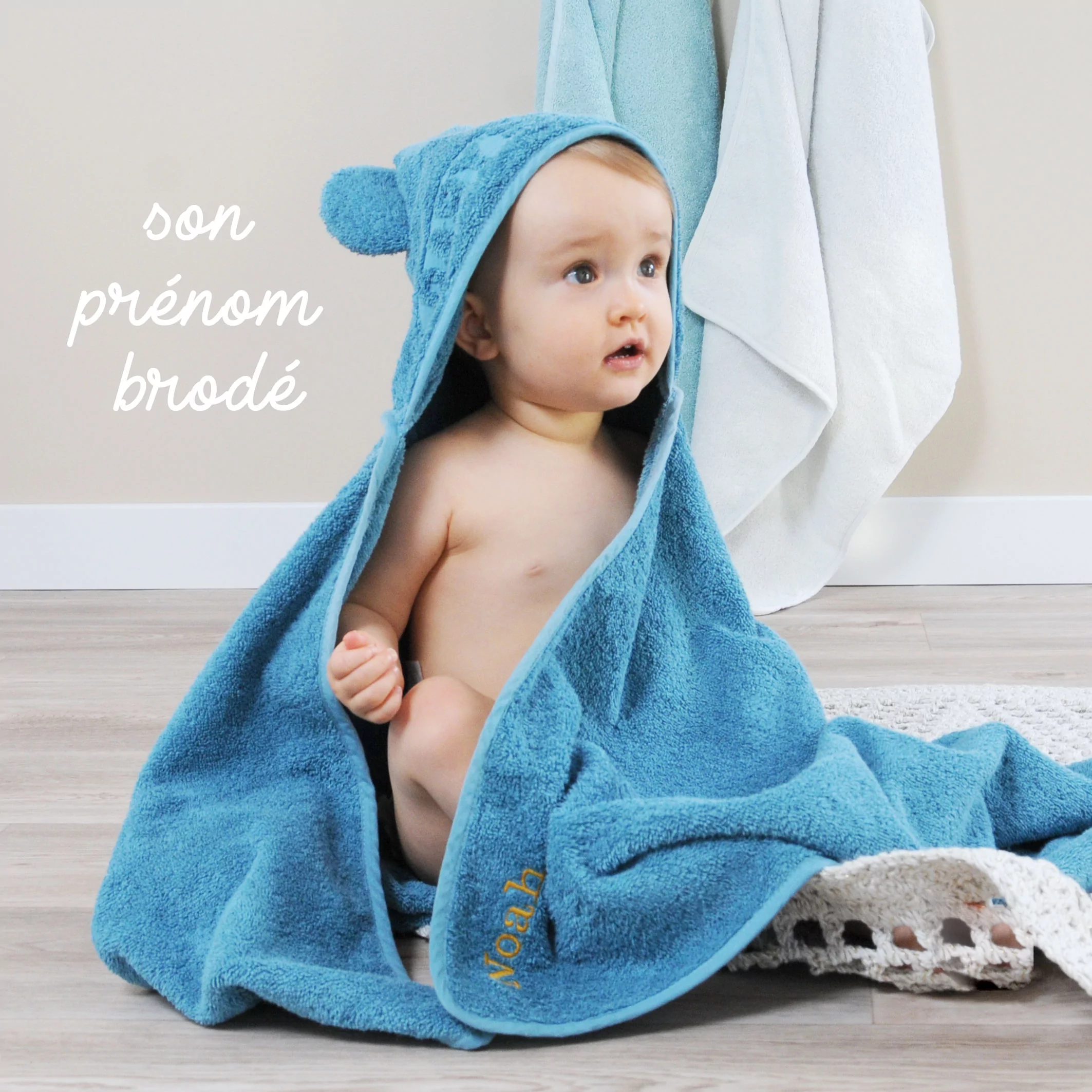 bébé avec sa cape de bain bleue brodée à son prénom